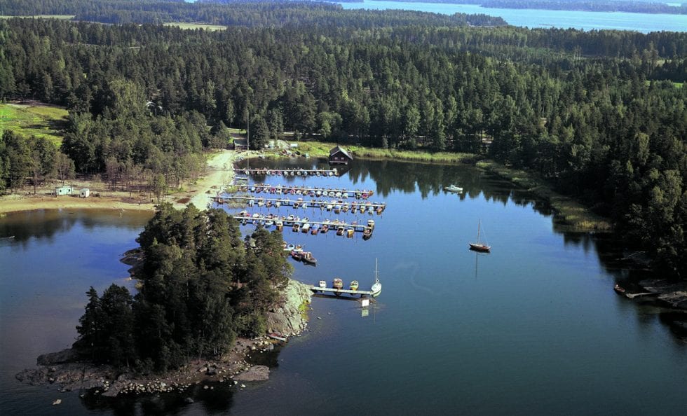 Kuva vuodelta 1972 Uutelan Mustalahden venesatamasta. Uuden asuinalueen myötä nimi Mustalahti vaihtui myöhemmin Aurinkolahdeksi. VUK:n venelaiturit olivat tuolloin lahden toisella reunalla, sa- moin kahvila Kampela oli hieman lännempänä nykyisesti paikastaan. Vanhan kahvilan kohdilla on nyt Uutelan kanavan suu. Uimaranta oli tuolloin melko lyhyt. Kuva: Helsingin kaupunginmuseo, Studio B. Möller 1972