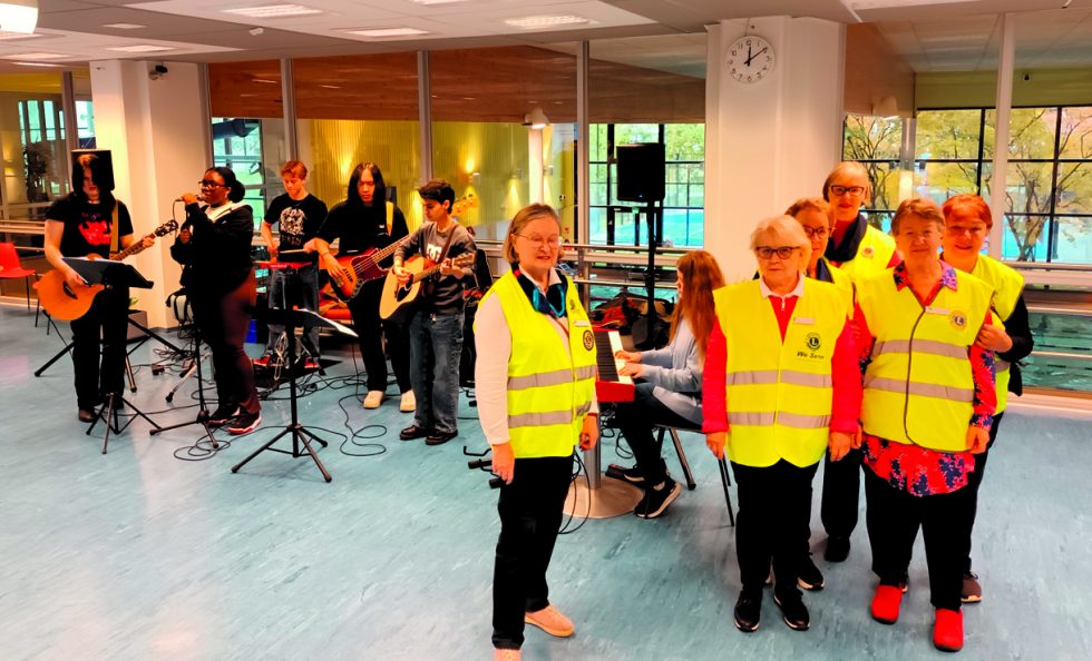 Lions Club Soihtujen reippaita naisia Urheilutalon aulassa. Taustalla musisoi Vuosaaren lukion bändi.