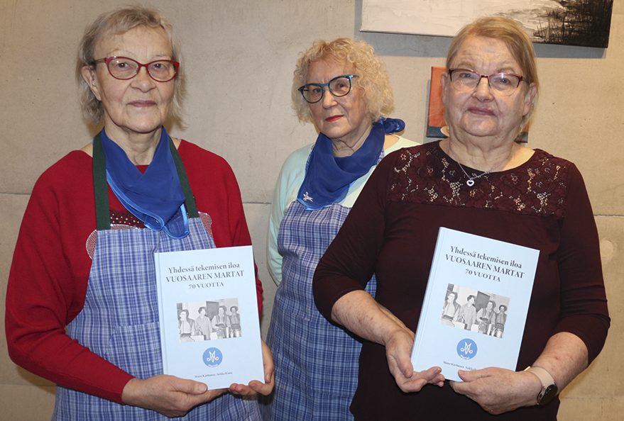 Edessä vasemmalla kirja kädessään Marttojen puheenjohtaja Maire Karttunen ja oikealla sihteeri Sirkka Rinne. Keskellä taustatyössä myös mukana ollut entinen puheenjohtaja Lili Järvinen.