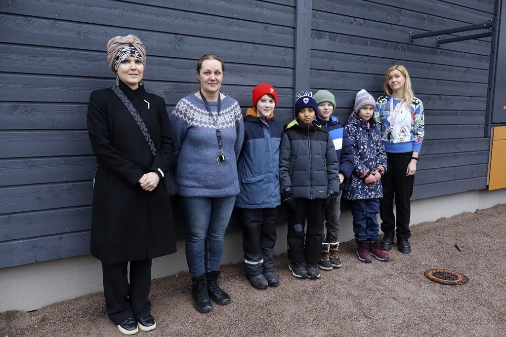 Lohikäärmeenpolun kaksikerroksisen paviljongin edustalla seisovat rehtori Suaad Onniselkä (vas.), virka-apulaisrehtori Jonna Huovinen, oppilaat Gunnar Lätti, Adam Al-Yazidi, Markus Lindroos, Sofia Lipsonen ja luokanopettaja Nea Nurmi ovat tyytyväisiä uusiin väistötiloihin.