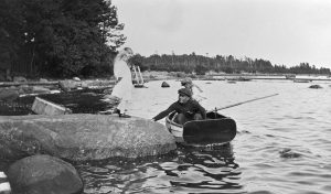 Kuva Kallahdenniemestä (Kallvik). Dorrit Greuling kivellä, Frank Greuling ja soutajapoika veneessä. Taustalla laivalaituri. Kuva: Greta Elmgren 1912, Helsingin kaupunginmuseo