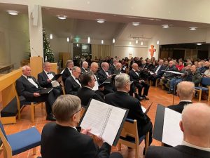 Yleisö ja laulajat kuuntelevat Teppo Lampelan lausumaa jouluevankeliumia.