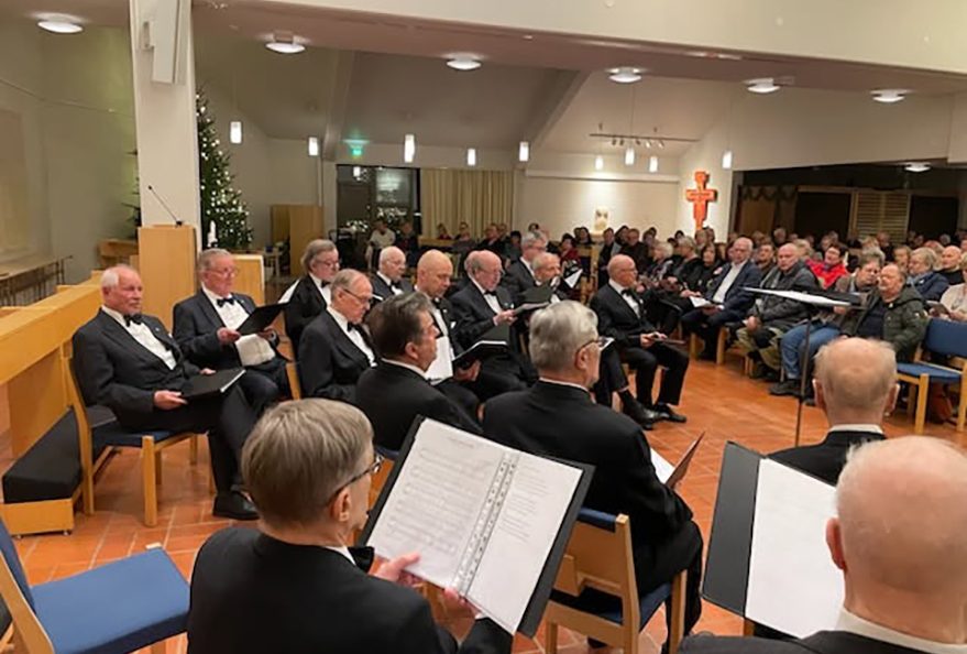 Yleisö ja laulajat kuuntelevat Teppo Lampelan lausumaa jouluevankeliumia.