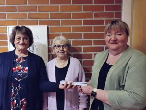 Kuvassa Vuosaaren seurakunnan diakoniatyön johtava viranhaltija Tuula Mäkinen (kuvassa oikealla) vastaanotti ruokalahjakortit. Soihduista klubipresidentti Sari Sepponen (vasemmalla) ja sihteeri Tellervo Ukkonen.