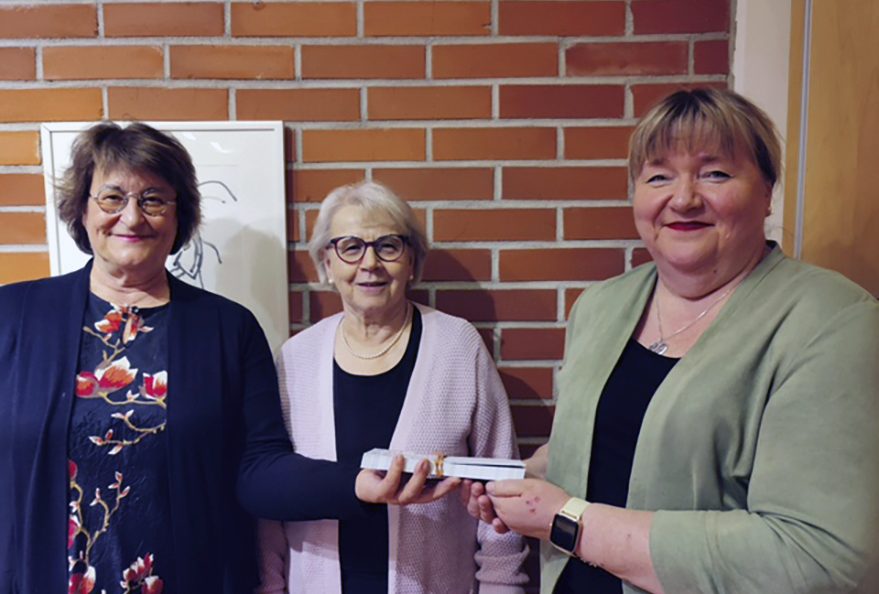 Kuvassa Vuosaaren seurakunnan diakoniatyön johtava viranhaltija Tuula Mäkinen (kuvassa oikealla) vastaanotti ruokalahjakortit. Soihduista klubipresidentti Sari Sepponen (vasemmalla) ja sihteeri Tellervo Ukkonen.